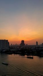 Scenic view of sea by buildings against sky during sunset