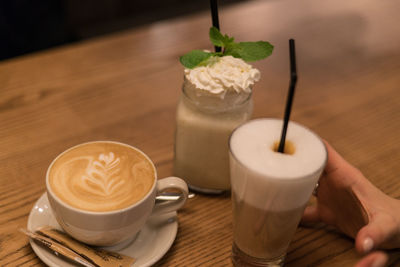 Cropped hand of person having coffee on table