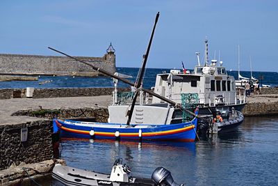 Boats moored at harbor against sky