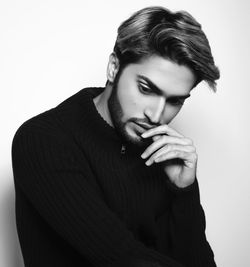 Thoughtful young man standing against white background