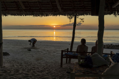 People sitting on beach during sunset