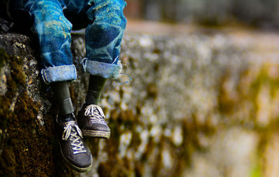 Lo section of man sitting on retaining wall