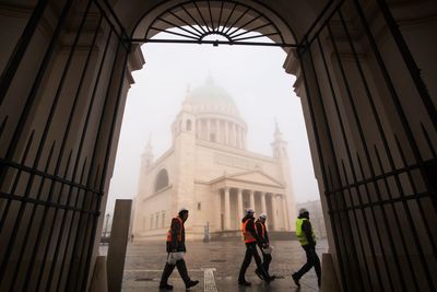 Workers walking against st nichola church during foggy weather