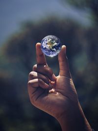 Close-up of hand holding crystal ball outdoors