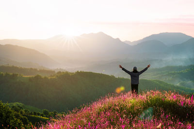 Man with arms outstretched on mountain at sunrise