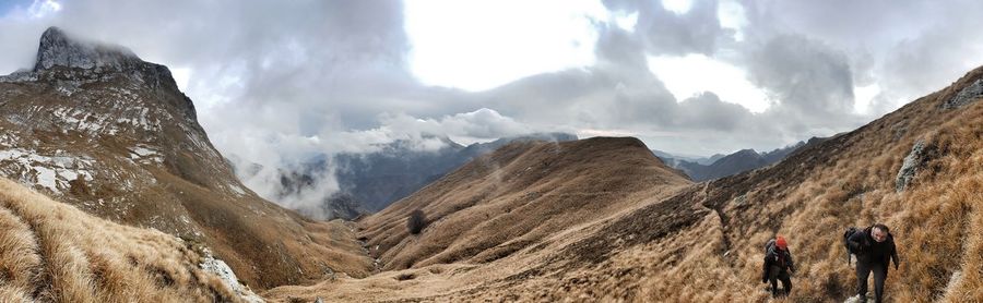 Panoramic view of people walking on mountain range against sky