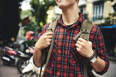 Midsection of man holding mobile phone while standing on street