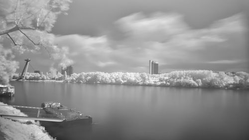 Panoramic view of factory by sea against sky