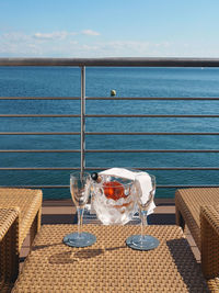 Champagne in container by flutes on table in balcony against sky