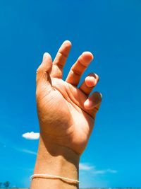 Close-up of hand against blue sky