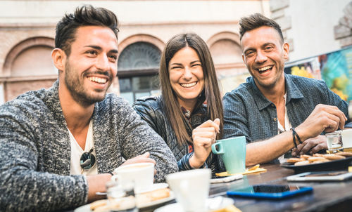 Smiling friends sitting at outdoor restaurant