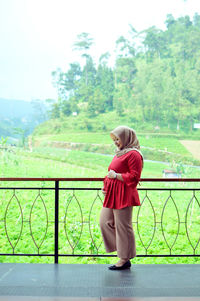 Pregnant woman walking in corridor against trees