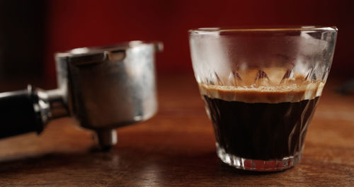 Espresso coffee with crema on wooden table with holder