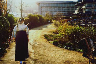 Rear view of woman walking on road