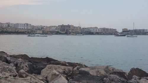 Buildings by sea against clear sky