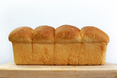Close-up of homemade bread loaf on wooden table against white background