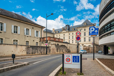 Road sign by building against sky