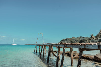 Pier over sea against clear blue sky