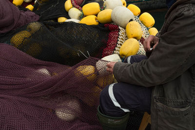 Midsection of man weaving fishing net at harbor