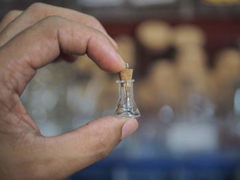 Close-up of person holding glass bottle with cork