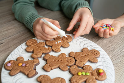 Cropped hand of boy decorating gingerbread cookie on table