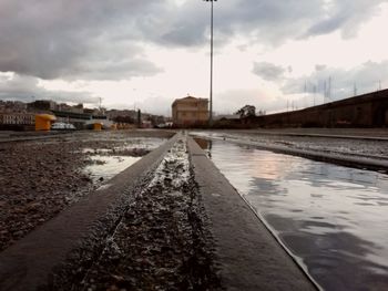 Surface level of wet railroad tracks against sky during rainy season