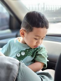 Close-up of cute boy looking away while sitting in car