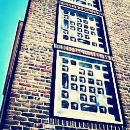 building exterior, architecture, built structure, low angle view, window, brick wall, blue, building, text, day, communication, outdoors, city, wall - building feature, no people, western script, residential building, brick, sky, sunlight