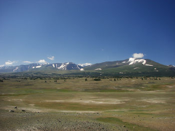 Scenic view of snowcapped mountains against blue sky