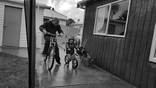 Full length of father with son riding bicycle at yard