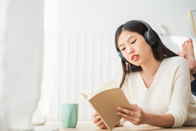 Young woman looking away while holding book