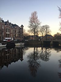 Reflection of buildings in lake against clear sky