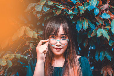 Portrait of young woman against plants