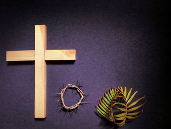Close-up of cross on table against black background