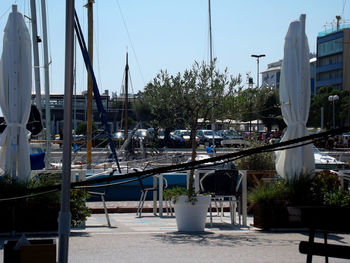 Sailboats moored on harbor against sky in city