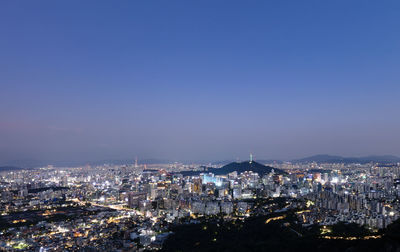 Illuminated cityscape against clear blue sky