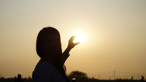 Silhouette hand against orange sky