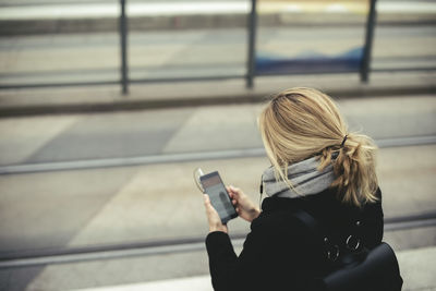 High angle view of mid adult businesswoman using mobile phone at tram station