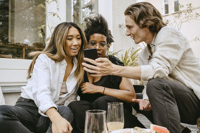 Young woman using mobile phone while sitting on table