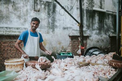 Portrait of happy butcher cutting meat at market stall