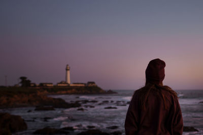 Rear view of man looking at sea against sky