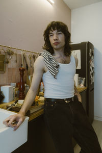 Contemplative young man wearing undershirt standing near kitchen counter at home