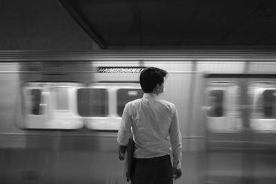 Rear view of man standing on train at railroad station
