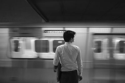 Rear view of man standing on train at railroad station