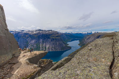 Tourists on trolltunga taking photos and admiring the fjord scenery.
