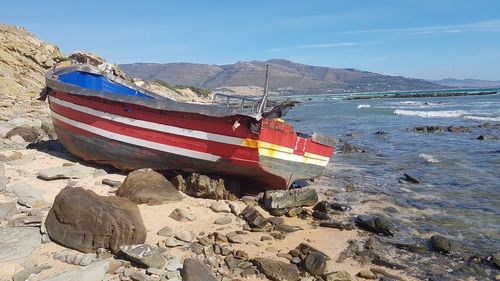 Boat moored on beach against sky