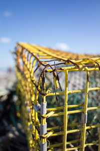 Close-up of yellow metal fence against sky