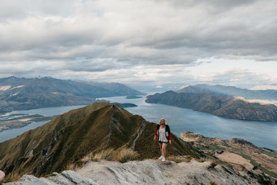 Woman standing on mountain against cloudy sky