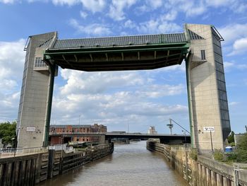 Low angle view of bridge over river against cloudy sky