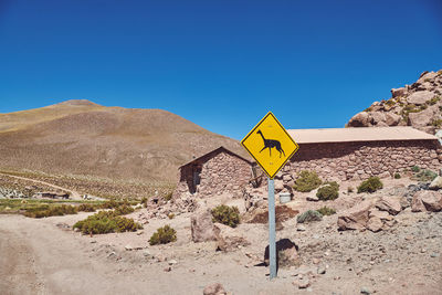 Road sign against clear blue sky